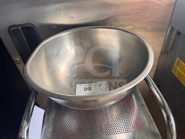 Stainless steel mixing bowl, lightly scratched, with auction tag reading "90" on interior, placed on perforated tray.