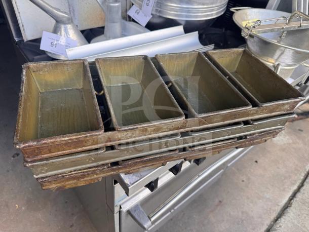 Lot of 3 vintage metal baking pans, stacked, showing wear and patina, ideal for collectors or baking enthusiasts.