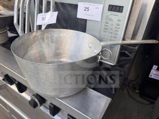Aluminum sauce pan with long handle, used condition, placed on a stovetop. Visible auction labels, no brand marks.