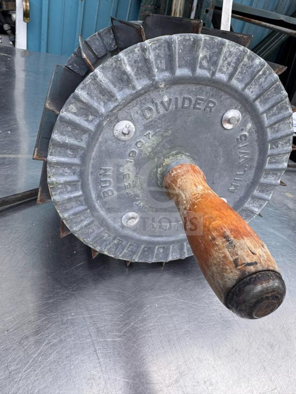 Vintage Miller bun divider with wooden handle, metal blades, and "BUN DIVIDER" markings. Patina indicates age and use.