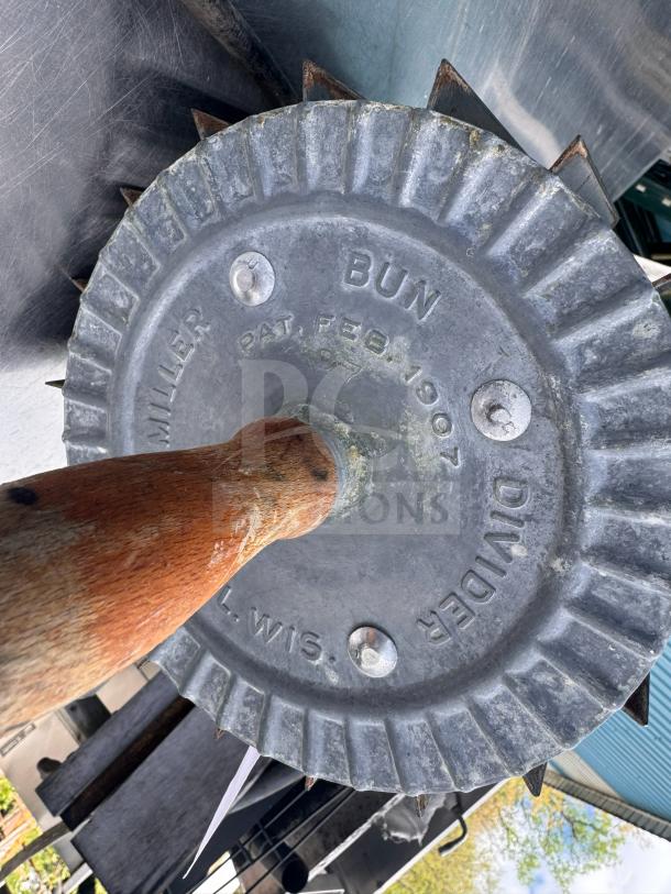 Vintage Miller bun divider with wooden handle, metal ridged edge, patent date Feb. 1907, worn condition, collectible kitchen tool.