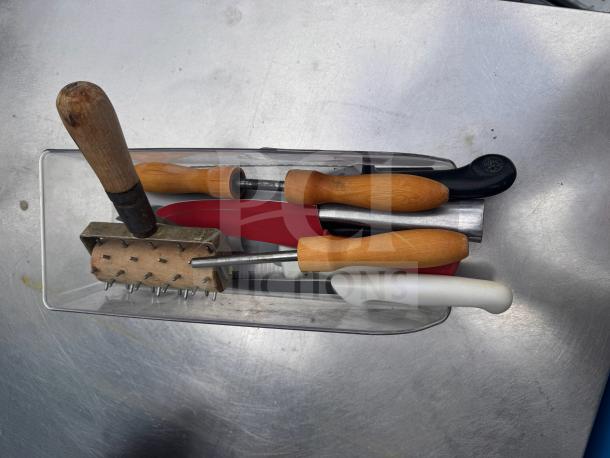 Assorted kitchenware set in a clear container, including knives and tools with wood and plastic handles. Used condition.
