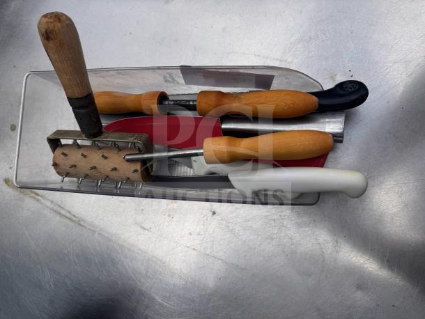 Assorted kitchenware with wooden, plastic handles and metal utensils in a transparent container. Used condition.