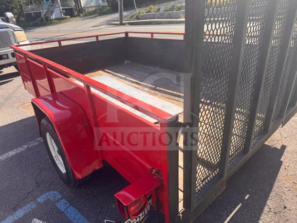 Red utility trailer with mesh ramp gate, wooden deck. Good condition, no title. Features include red side panels and fenders.
