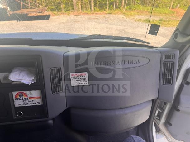 Interior of International box truck showing dashboard with warning labels and Idealease maintenance check sticker.