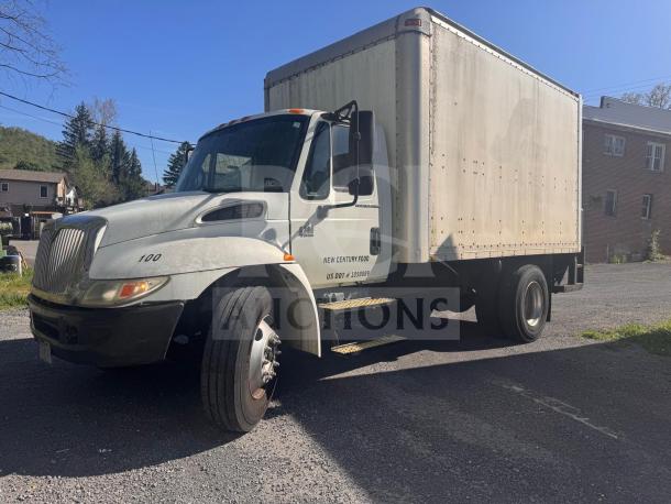 Box truck with white cab and large cargo area, "New Century Food" branding, visible wear, parked on gravel.