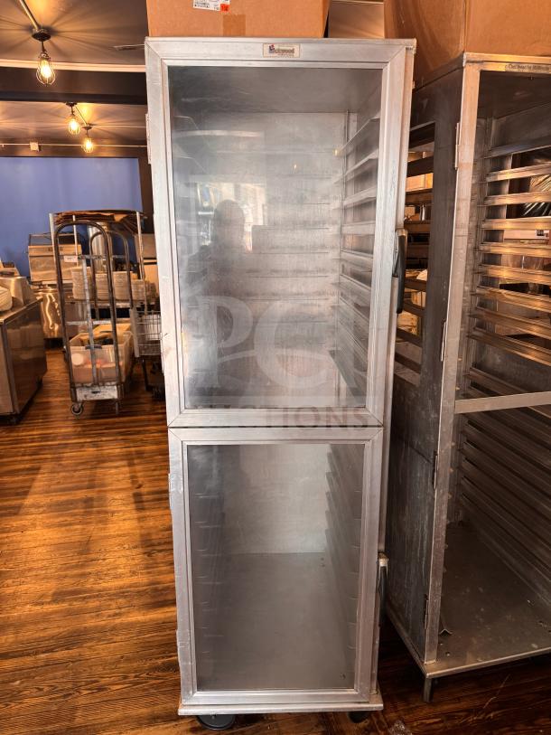 Aluminum sheet pan cabinet with clear doors, used, on wheels, Backguard label, for professional kitchen storage.