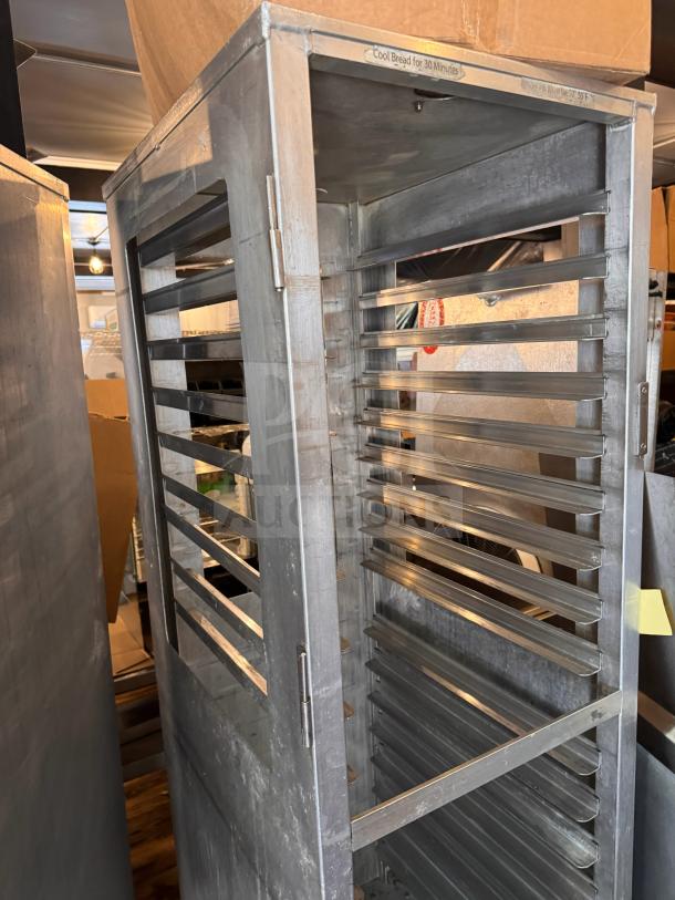 Stainless steel sheet pan rack with multiple slots. Sturdy construction, slight wear visible. Marking reads "Cool Bread for 30 Minutes."
