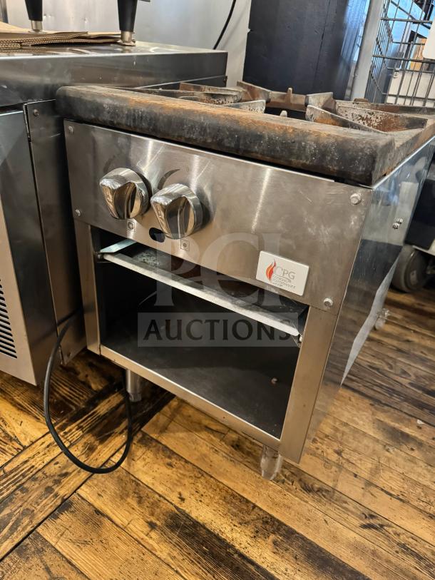 CPG natural gas stock pot range with dual knobs, steel body, and visible storage. Shows some wear, CPG logo visible.