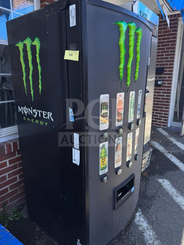 Monster Energy vending machine with logo, multiple product selections, and functional payment system. Black exterior with minor wear.