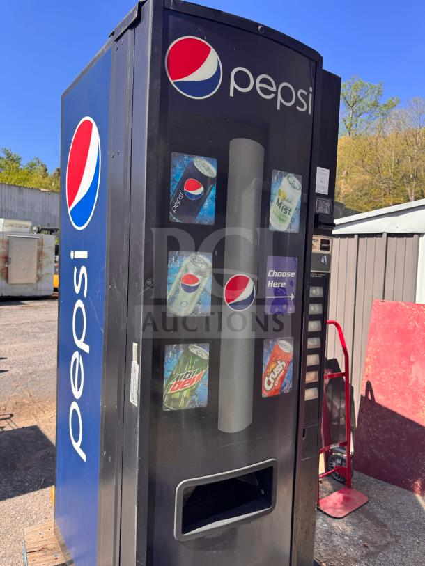 Pepsi vending machine, metal exterior, displaying various soda options. Condition shows wear, missing key.