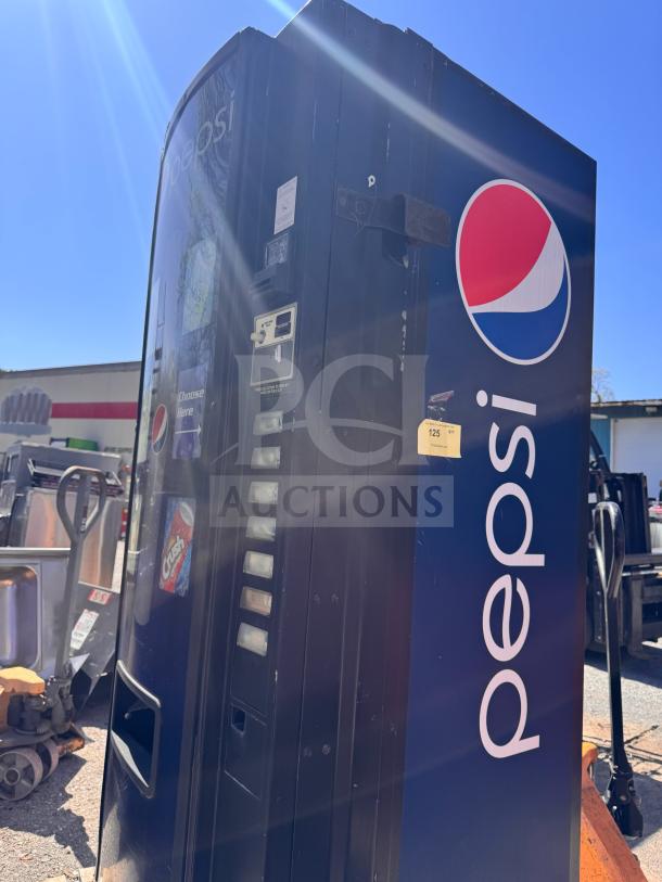 Pepsi vending machine, blue with logo, missing key, features coin slot and selection panel. Some surface wear visible.