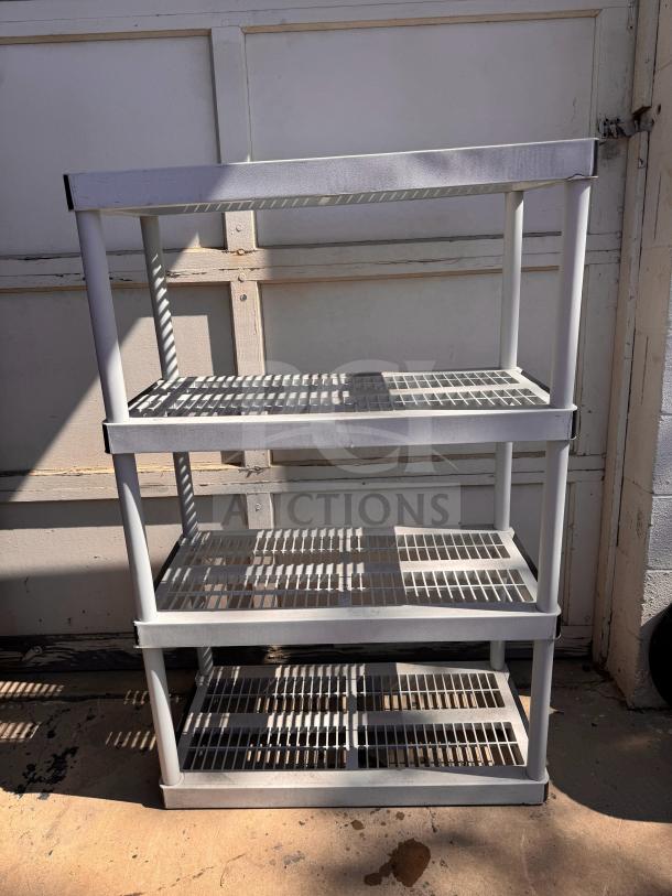 Plastic storage shelving unit with four tiers, white color, used, sturdy construction, suitable for garage or basement storage.