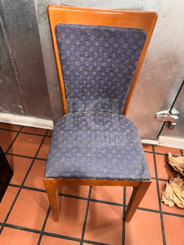 Wooden dining side chair with blue patterned fabric seat and backrest. Slight wear on cushion. Classic style.