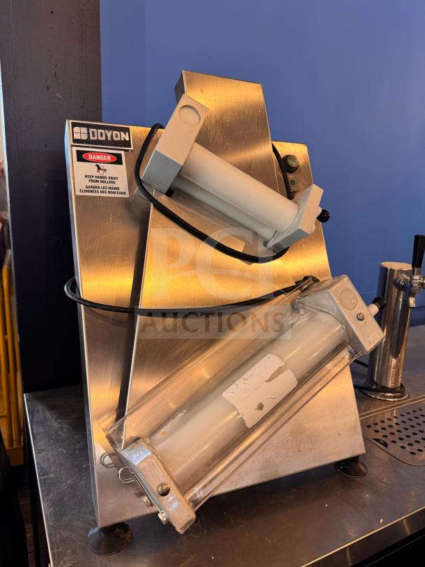 Doyon DL12DP countertop dough sheeter, stainless steel, dual-roller design, warning label visible, good condition.