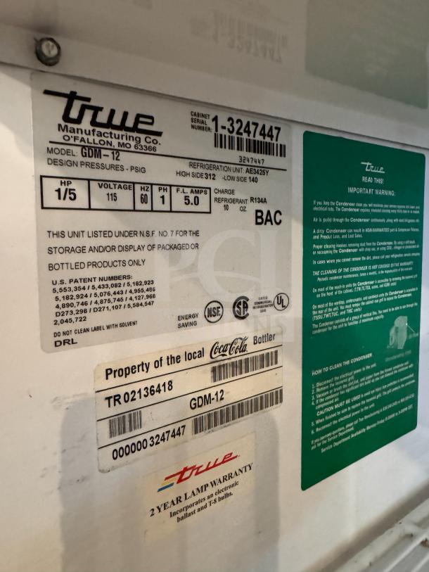 Close-up of True GDM-12 Cooler merchandiser label, showing model, serial number, specifications, and two-year lamp warranty.