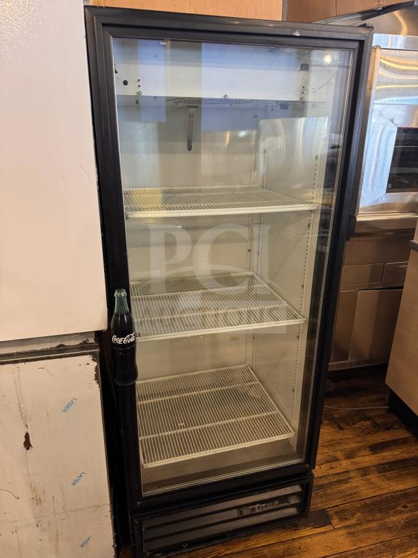 True GDM-12 cooler merchandiser, glass door, three wire shelves, black frame, used condition, suitable for drinks display.