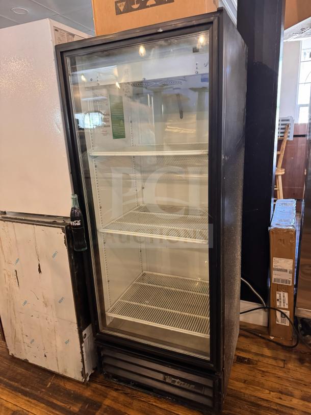 True GDM-12 cooler merchandiser, features two shelves, glass front, black exterior, appears in good condition.