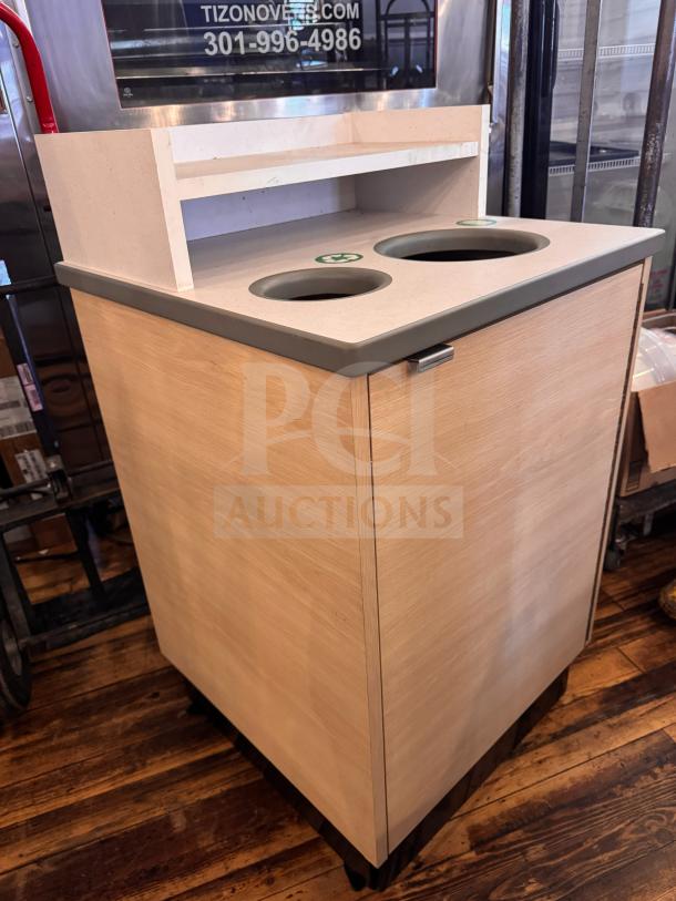 Wooden waste receptacle with dual circular openings, countertop, and shelf. Good condition, branded with recycling symbols.