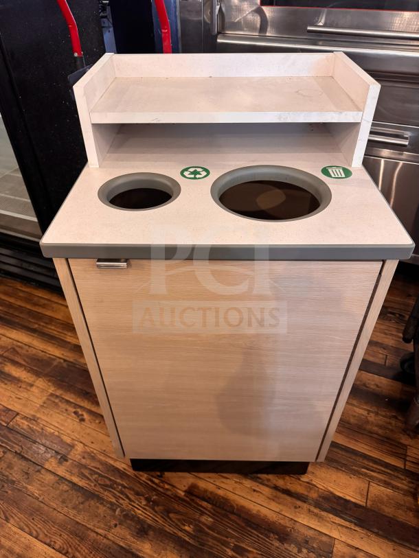 Modern waste receptacle with dual compartments, recycling and trash labels, shelf on top. Light wood finish, excellent condition.