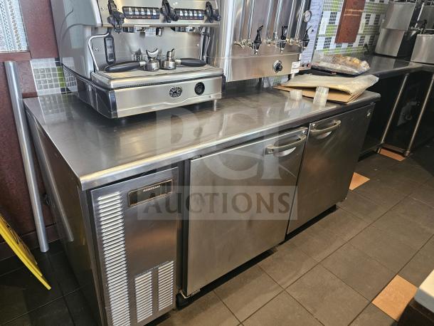 Stainless steel worktop refrigerator with dual doors and integrated handles, features Hombracke branding, in good condition.