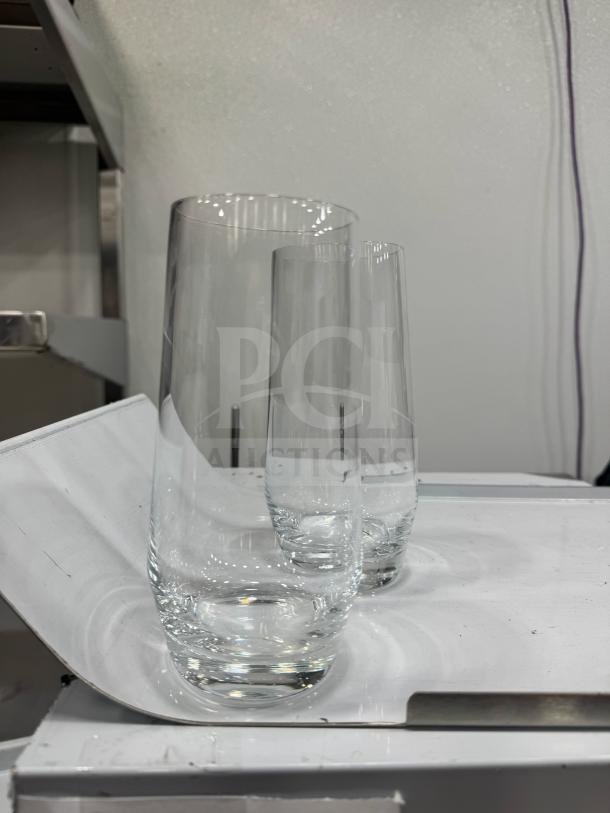 Tall clear long drink glass on white surface, sleek design, excellent condition, ideal for cocktails or beverages.