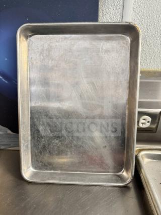 Aluminum baking sheet with visible surface scratches, rectangular shape, good condition, resting on a stainless surface.