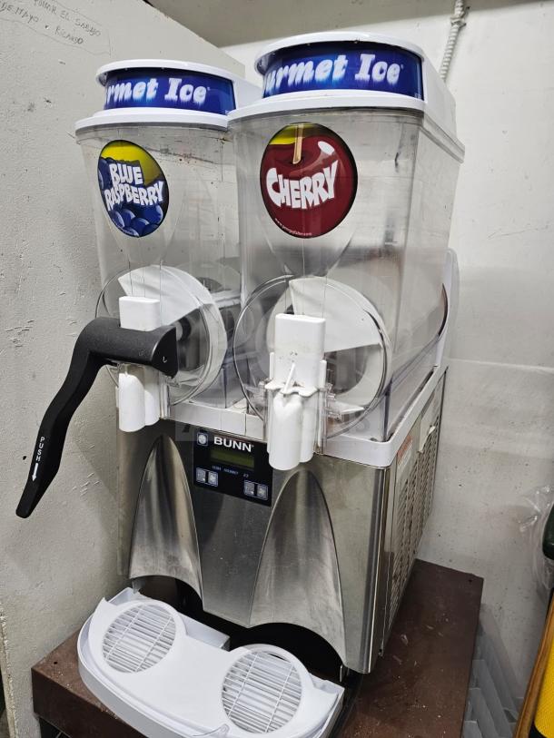 Bunn Ultra-2 Gourmet Frozen Drink Machine, dual tanks labeled "Blue Raspberry" and "Cherry," stainless steel front, good condition.
