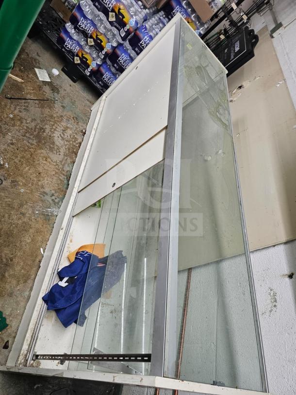 Glass and metal display case, showing wear with visible scratches and dirt. Some cleaning supplies inside. Sturdy construction.