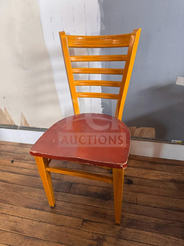 Wooden dining chair with ladder back design and brown seat. Visible wear on seat edges and surface. Natural wood finish.