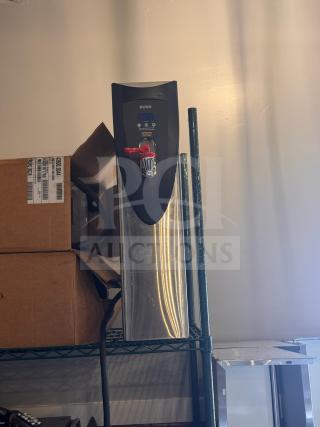 Brand new Bunn hot water dispenser in stainless steel, with digital display and red faucet, resting on a storage shelf.