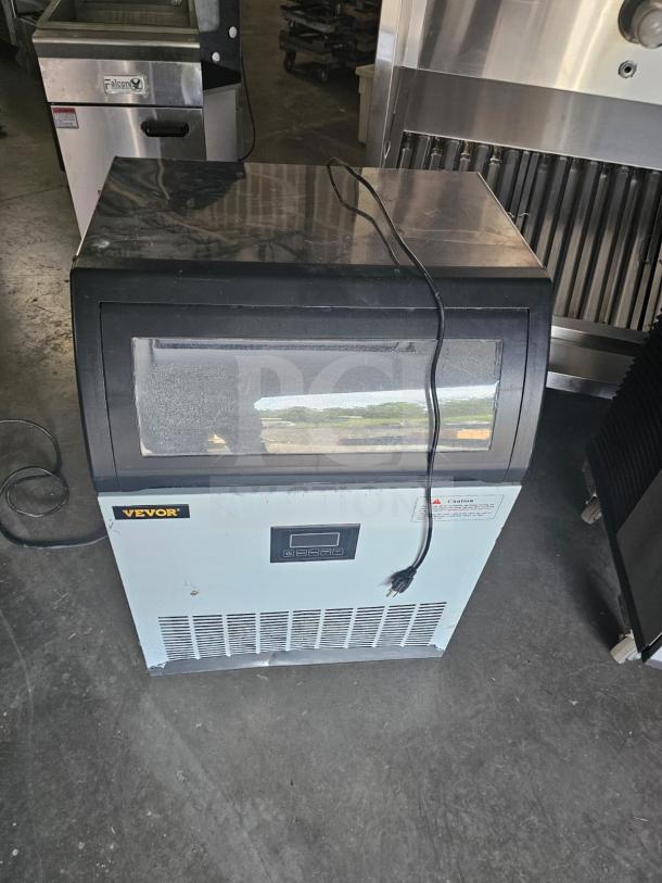 VEVOR SKF-E120F commercial ice maker, black and silver, front digital display, visible plug, lightly scuffed exterior.