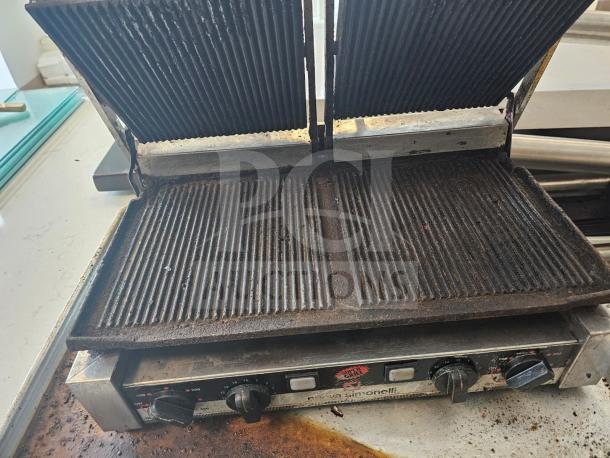 Nuova Simonelli Super Grill Commercial Double-bay panini grill, used condition, features adjustable heat knobs and ribbed plates.
