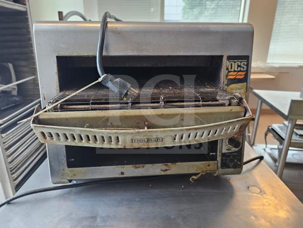 Holman QCS Series commercial conveyor toaster, used condition, visible control knobs, Holman logo, and power cord attached.