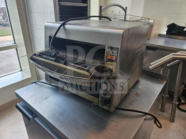Holman QCS Series commercial conveyor toaster, stainless steel, used condition, visible control knobs, branding label on side.