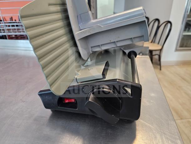 Sportsman Series meat slicer, used condition, gray and black finish, adjustable thickness dial, resting on metal counter.