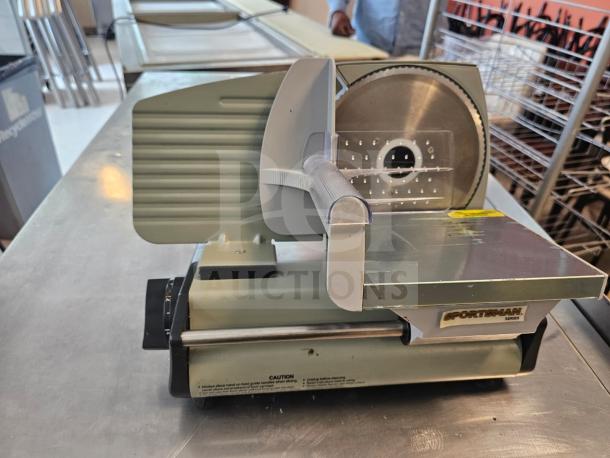 Sportsman Series meat slicer, silver and green, in used condition. Features adjustable blade and safety guard, labeled "Sportsman Series."