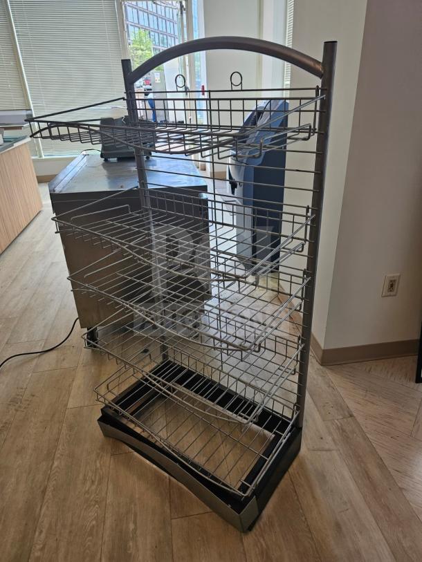 5-tier wire merchandising display on wheels, used, with adjustable shelves and sturdy metal frame for retail use.