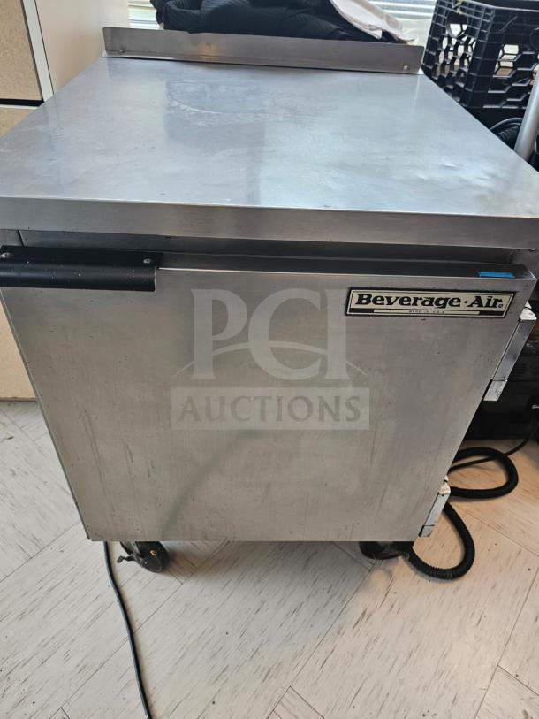 Beverage-Air WTF27A commercial undercounter refrigerator, stainless steel, visible wear, black handle, on wheels.