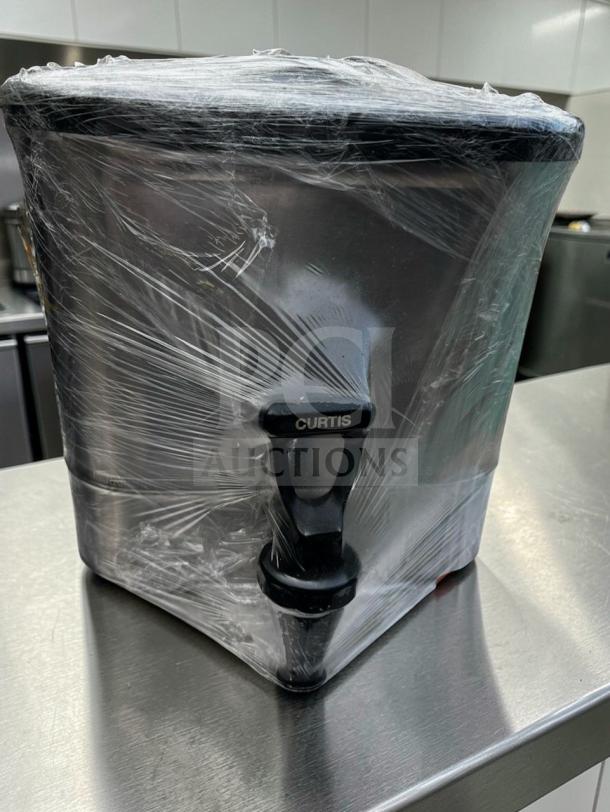 Stainless steel Curtis commercial beverage dispenser in flawless condition, wrapped in plastic, featuring a large capacity and Curtis-branded tap.