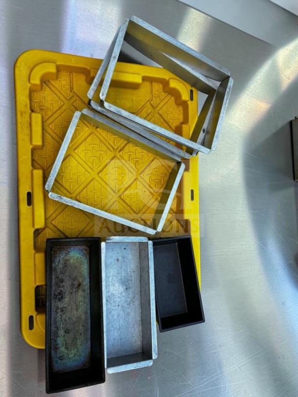 Assorted commercial baking pans and cake frames on a yellow tray. Stainless steel and aluminum, excellent condition. Model BAK-S-PAN-0662.