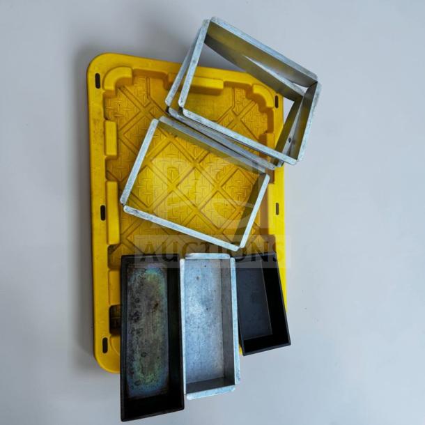 Assorted commercial baking pans and cake frames on a yellow tray; stainless steel and aluminum; professional condition.