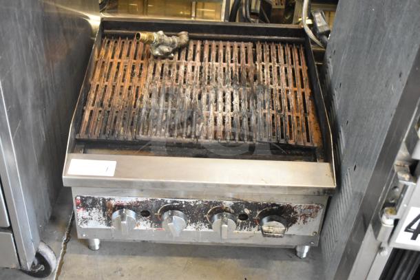Commercial countertop gas-powered charbroiler grill with metal grates, showing signs of wear. Four control knobs at the front.