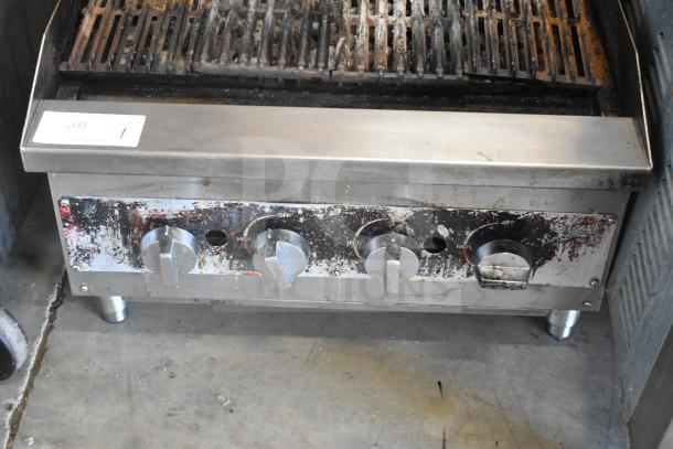 Commercial countertop gas charbroiler grill with multiple burners; visible wear and grime on stainless steel surface.