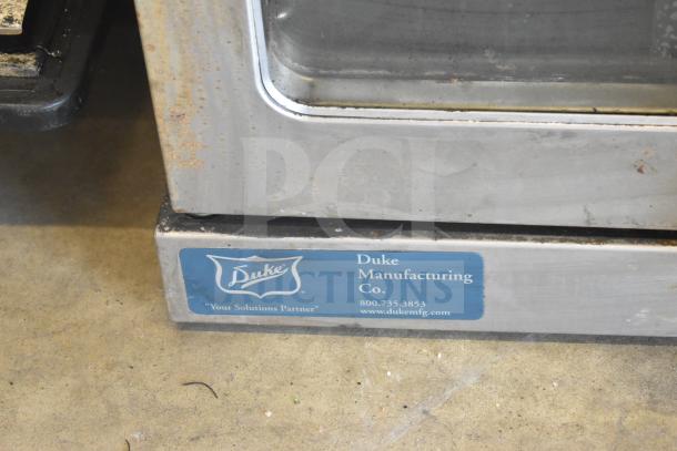 Duke stainless steel convection oven with view-through doors, thermostatic controls, metal legs; Duke Manufacturing Co. label.