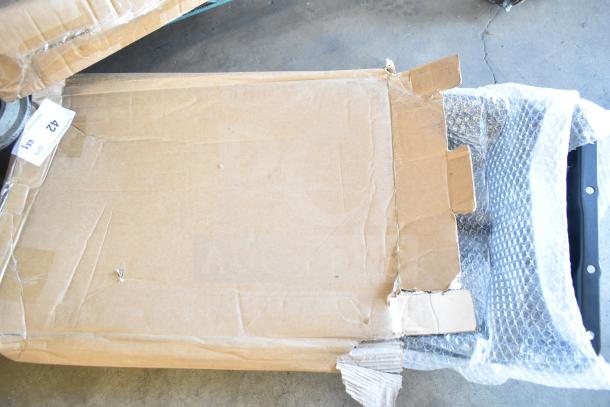 Three new scratch and dent items in opened box, including shower caddy. Visible bubble wrap and item tag marked "42."