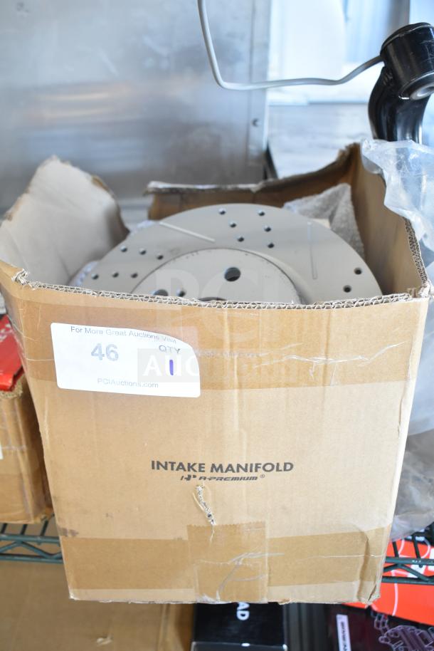 Cardboard box labeled "Intake Manifold" showing contents with minor scratches and dents. Box also shows auction label.