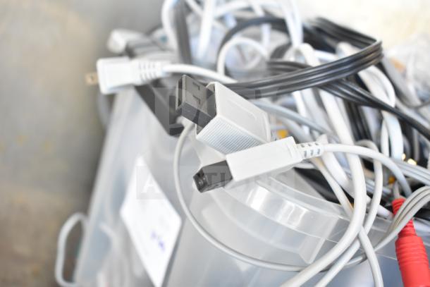 Lot of assorted cables and gaskets piled in a clear container, showing various connectors and wires. Condition appears used.