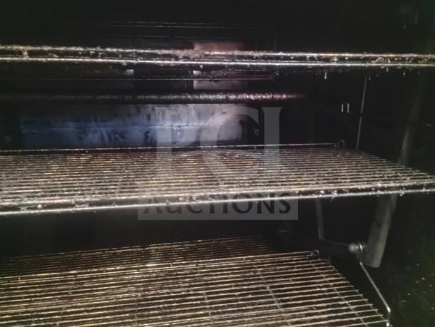 J&R Manufacturing Oyler 1300E smoker interior with stainless steel racks; wood/charcoal fired, electric heat, used condition.