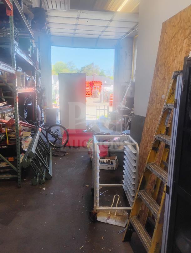 A workspace with various tools and equipment. A large object is being moved through an open garage door.